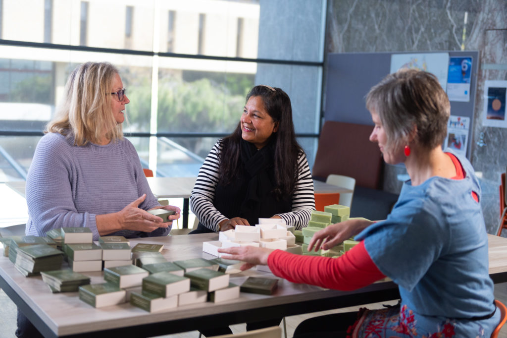 three women packaging bars of soap 