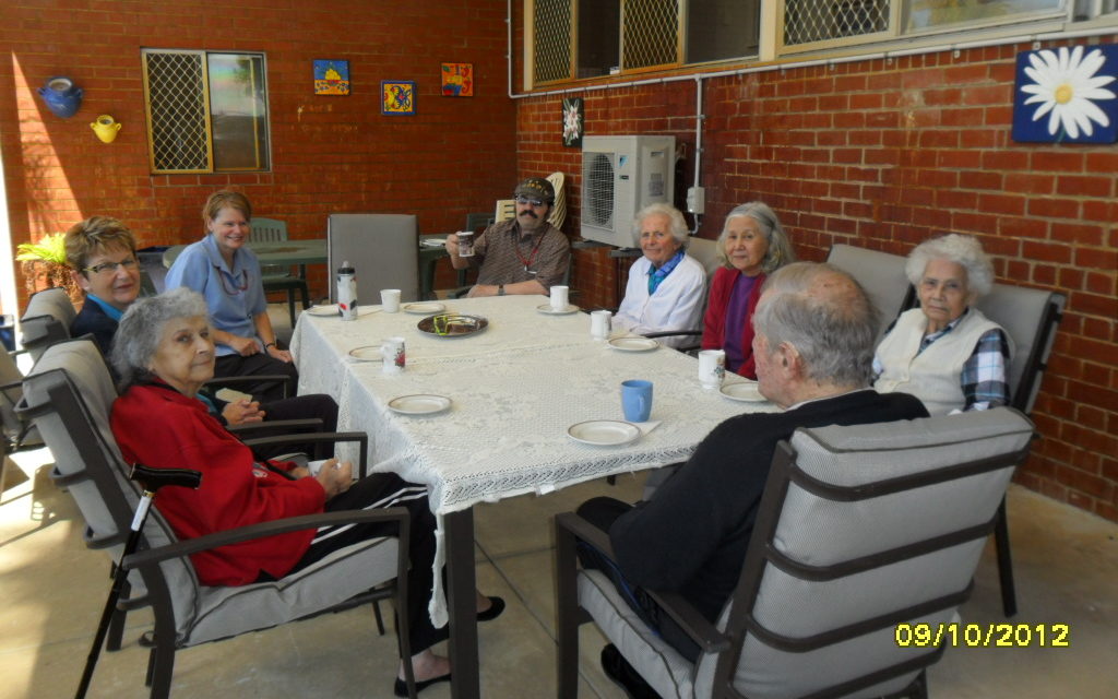 Davis house residents sitting around an outdoor table drinking cups of coffee