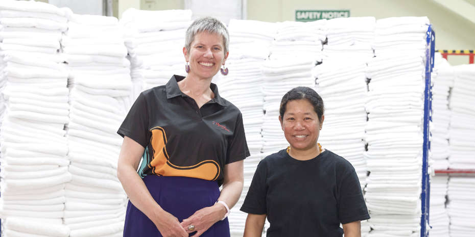MercyCare staff member with Refugee employee in front of clean sheets