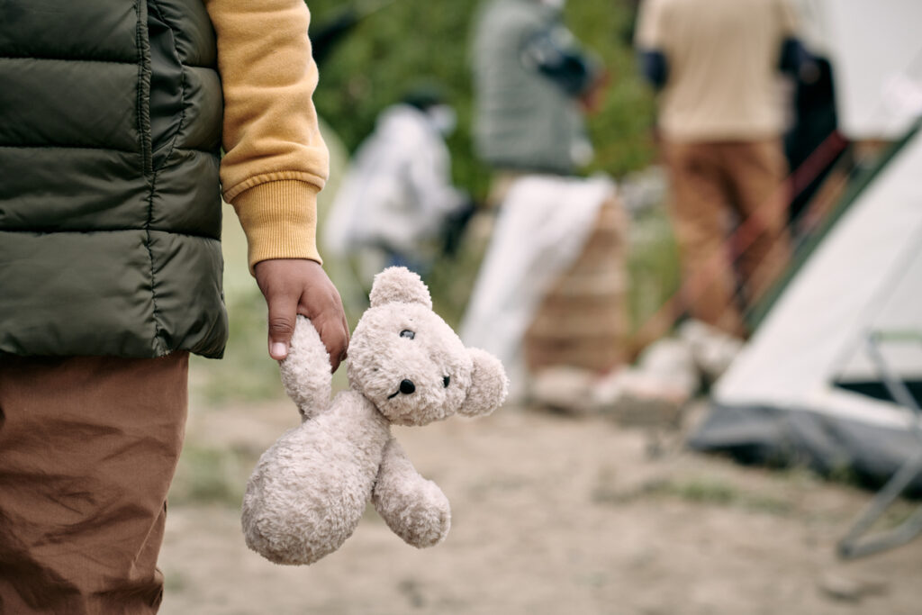 Humanitarian minor holding toy bear in one hand