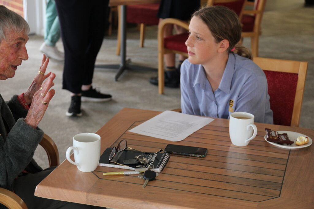 A student listening to a story from a Mercy Village resident